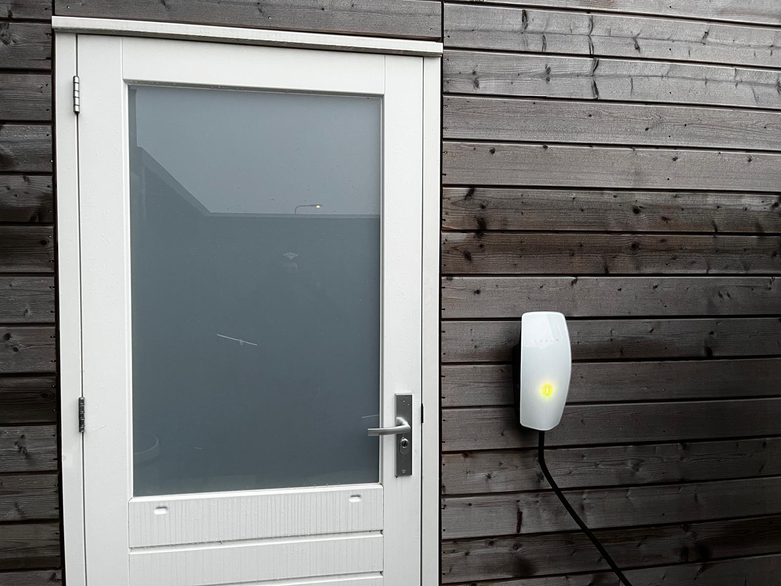 Tesla laadpunt gemonteerd naast een buitendeur