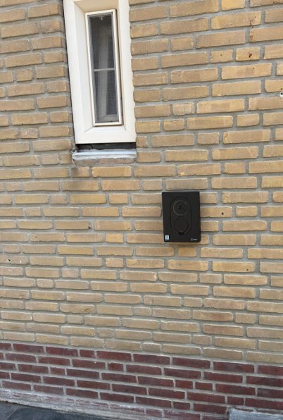 Zwarte laadpaal gemonteerd aan een gemetselde gevel